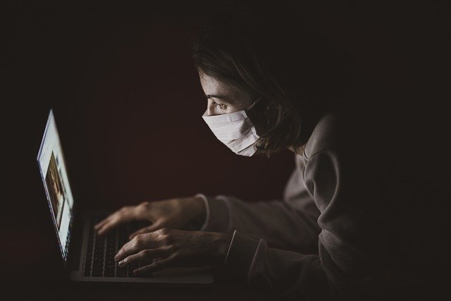 woman with face mask on laptop