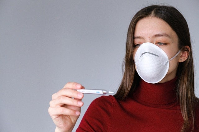 Woman wearing face mask looking at thermostat