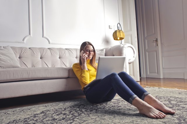 woman talking on phone while on laptop