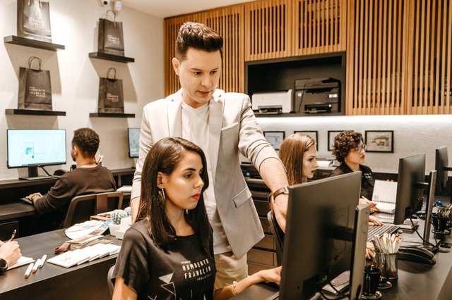 man teaching woman in front of a monitor