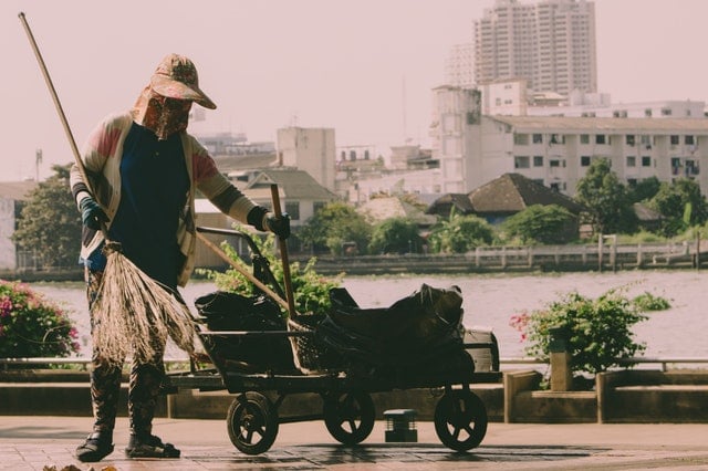 person holding broom and cart